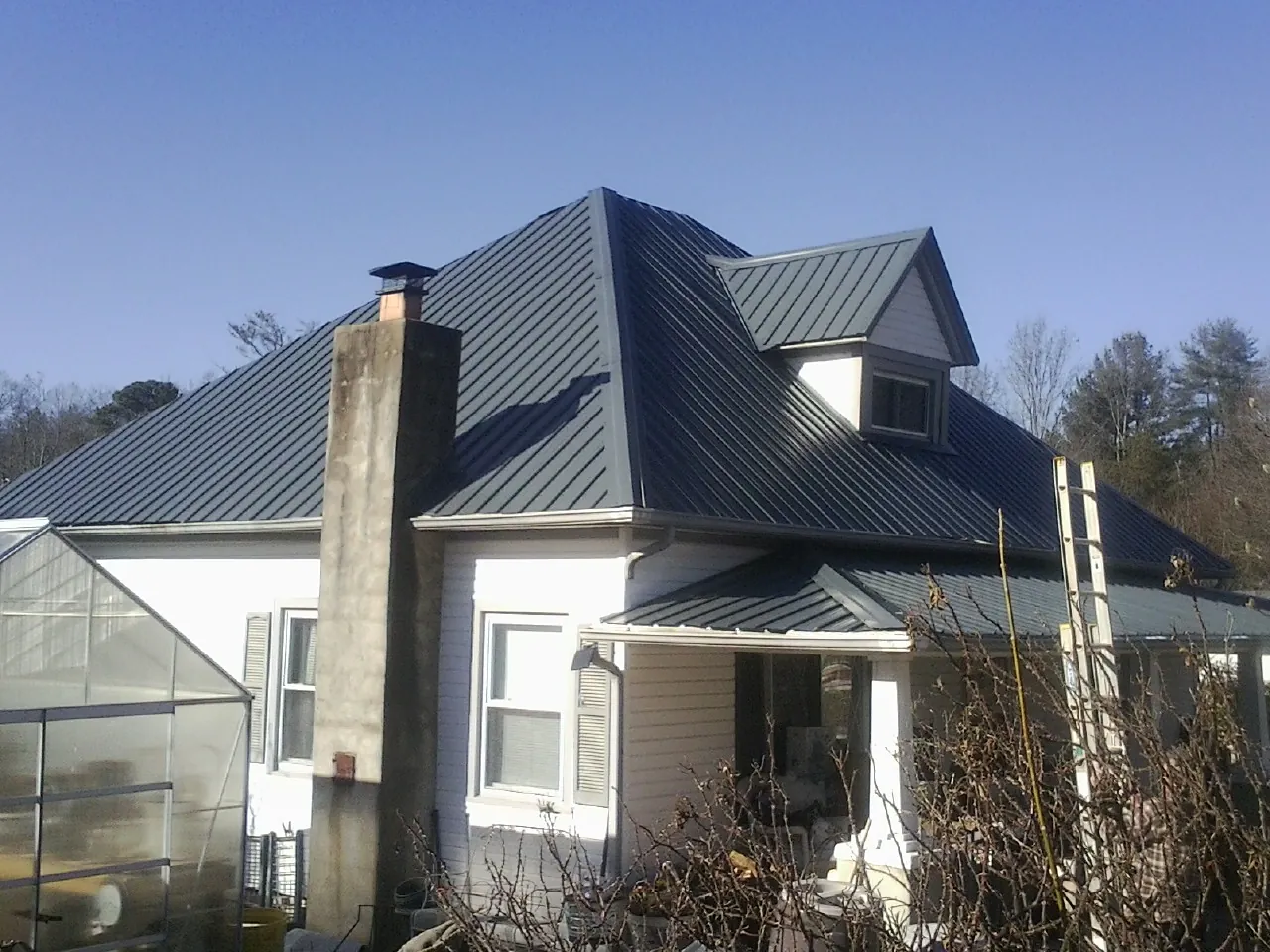 Dark blue standing seam metal roof on a white farmhouse with dormer — Slate & Tile Roof Repair by Roofing Brothers in Asotin