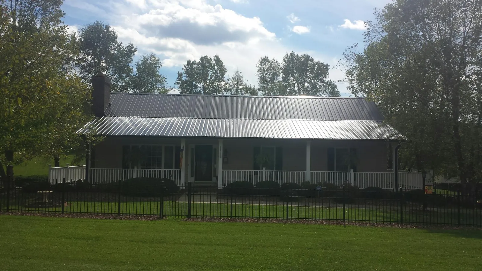 Gray metal roof on a brick ranch with a full width front porch — Gutter Guard Installation work by our crew in Asotin